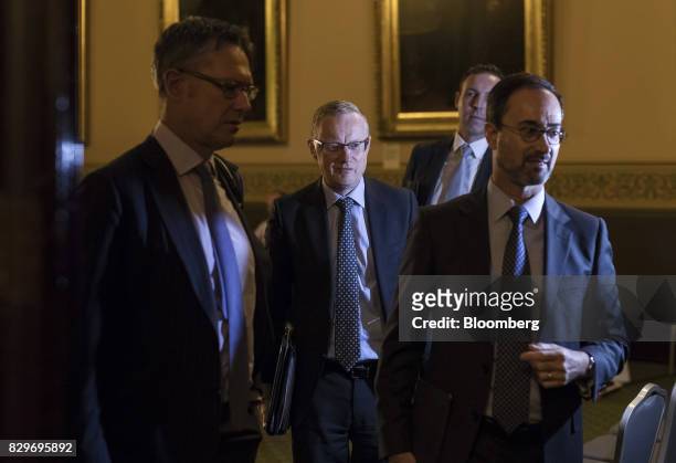Philip Lowe, governor of the Reserve Bank of Australia , center, departs a hearing before the House of Representatives economics committee in...