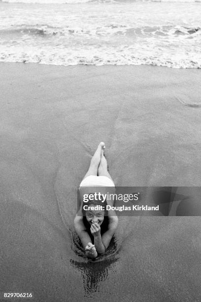 French actress Jeanne Moreau laying on the wet sand at a beach in Cuernavaca Mexico, 1965.