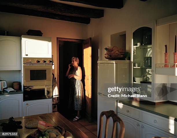 woman speaking on telephone in kitchen - landline phone home stock pictures, royalty-free photos & images