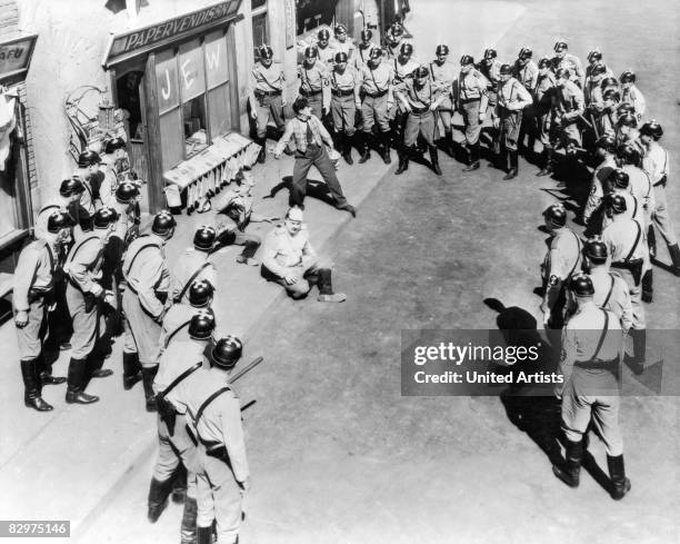 English-born actor Charles 'Charlie' Chaplin holds off a group of fascists armed with nightsticks and rifles in a still from the film, 'The Great...