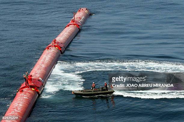 Worker ties a Portuguese flag to an off-shore electricity generator based on wave power off of Portugal's Atlantic coast near the northern town of...