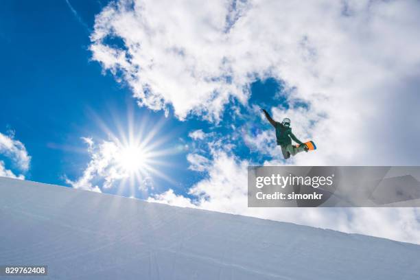 male snowboarder jumping over half pipe - half pipe stock pictures, royalty-free photos & images