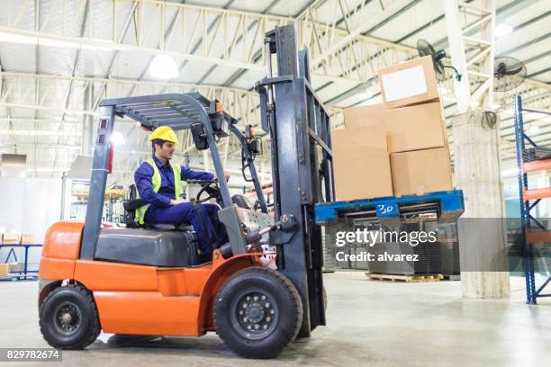 worker driving a forklift in warehouse - forklift truck stock pictures, royalty-free photos & images