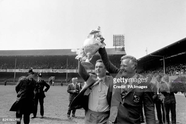 Derby County manager Brian Clough and his assistant Peter Taylor show off the League Championship trophy to the jubilant Derby fans who had packed...