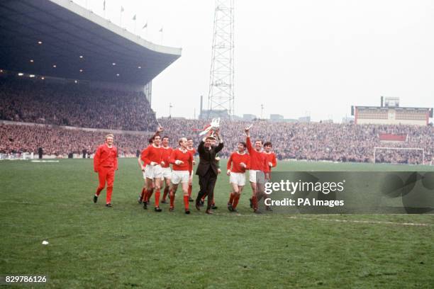 Manchester United manager Matt Busby holds the League Championship trophy aloft as he and his players parade it around Old Trafford: Denis Law, Bill...