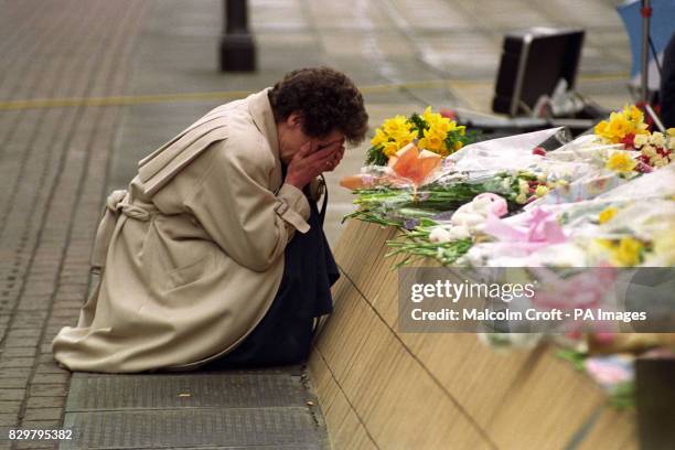 A WOMAN WEEPS BY THE FLOWERS AT THE SCENE OF THE BOMB ATTACK IN WARRINGTON.