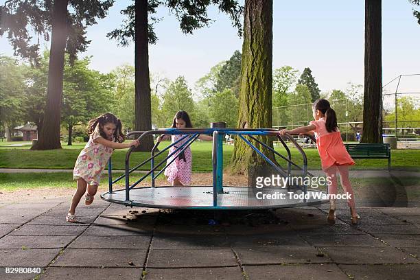 kids on carousal in playground - playground stock pictures, royalty-free photos & images