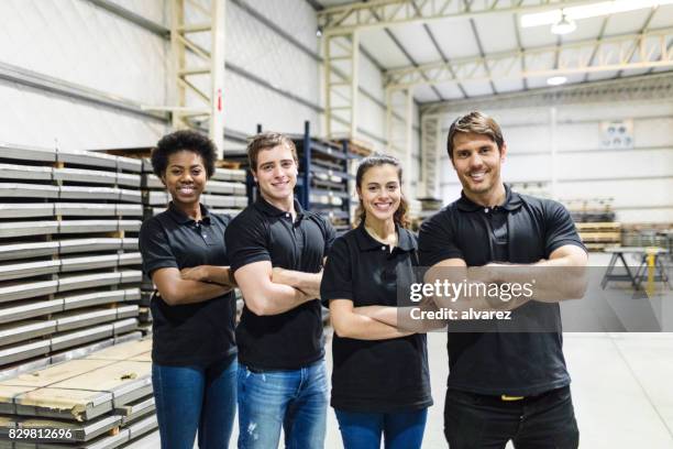 jongeren staande samen in de fabriek - folded arms stockfoto's en -beelden