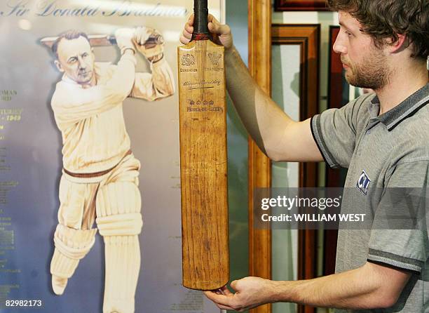 An employee from the Charles Leski Auction House holds up the first cricket bat used by Sir Donald Bradman in his Test career and which will be...
