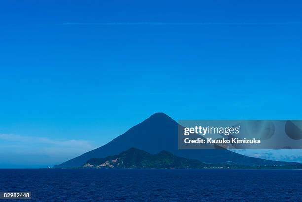 mt.kaimondake from seaside,with vapor trail - kazuko kimizuka stockfoto's en -beelden