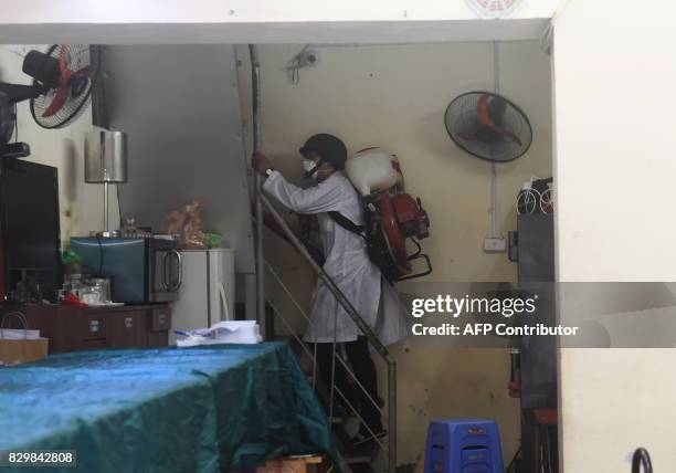 Municipal worker climbs the stairs as he sprays chemicals to kill mosquitos at a residential home in downtown Hanoi on August 11, 2017 as authorities...