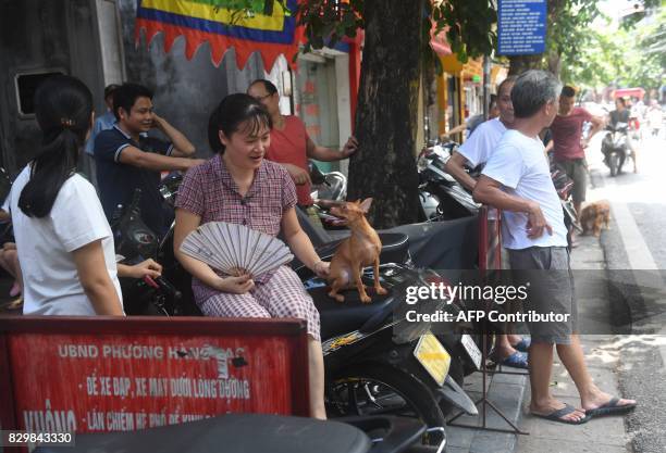 Woman sits on a shooter with a dog as residents wait outside their homes while municipal workers spray chemicals to kill mosquitos inside the...