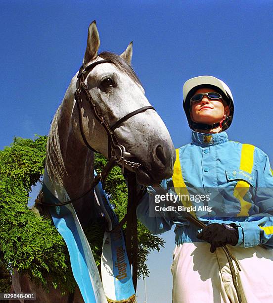 female jockey standing with horse wearing sash, close-up - racing silks fotografías e imágenes de stock
