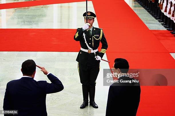 Venezuelan President Hugo Chavez salutes as Chinese President Hu Jintao accompanies him to view an honour guard during a welcoming ceremony inside...