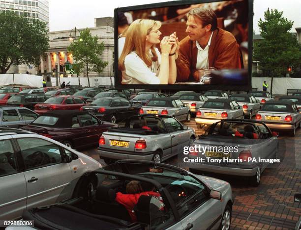 Couples sit in a variety of cars, watching the new Kevin Costner movie 'Tin Cup' at a drive-in cinema in Birmingham today , as manufacturers...