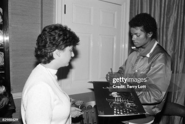 Michael Jackson signing the sleeve of The Jacksons 'Triumph' album. Michael is in London to accept a gold disc for the album, London, 1980.