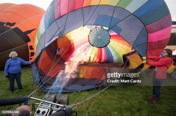 Hot air balloons are inflated and take to the skies as they participate in the mass assent at sunrise in the main arena on the second day of the...