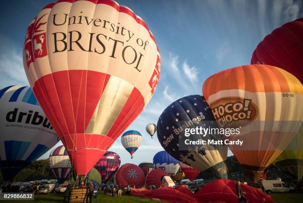 Hot air balloons are inflated and take to the skies as they participate in the mass assent at sunrise in the main arena on the second day of the...