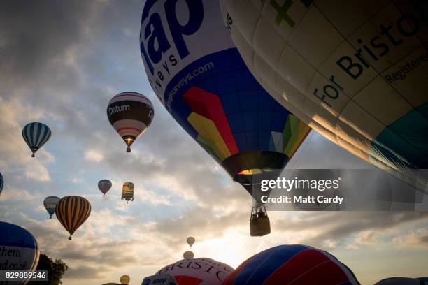 Hot air balloons are inflated and take to the skies as they participate in the mass assent at sunrise in the main arena on the second day of the...