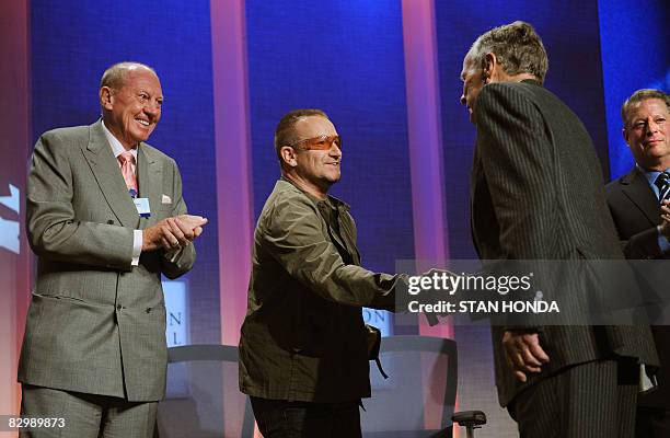 Bono , lead singer U2 shakes hands with former US President George H.W. Bush as E. Neville Isdell , Chairman of the Board of Directors, The Coca-Cola...