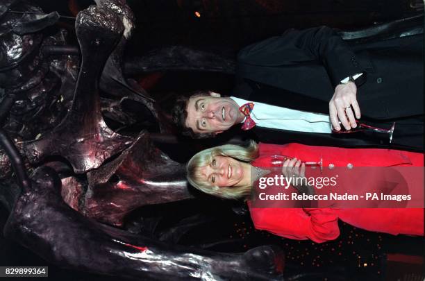 Television presenters Lynn Faulds Wood and her husband John Stapleton posing in front of the skeleton of a dinosaur at London's Natural History...