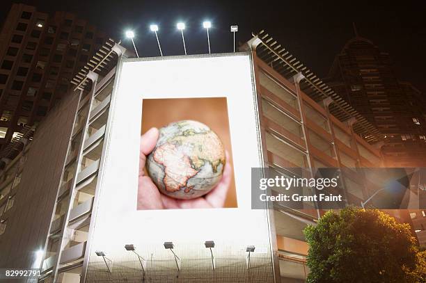 billboard display at night showing man holding glo - insegna commerciale foto e immagini stock