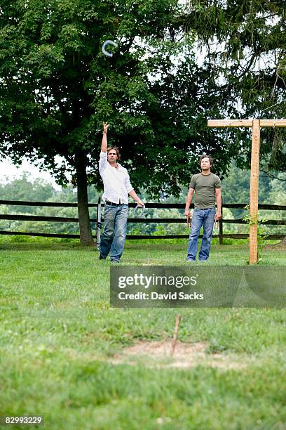 two men playing horseshoes - horseshoe stock pictures, royalty-free photos & images