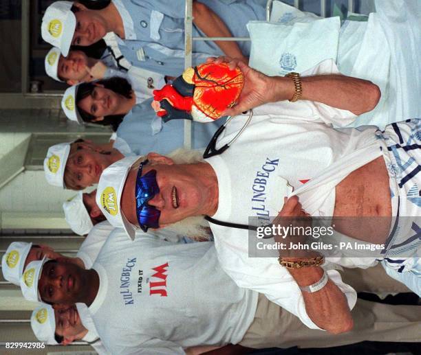 Sir Jimmy Savile holds up a plastic heart and shows off the scars from his operation as he leaves Killingbeck Hospital in Leeds today after having...