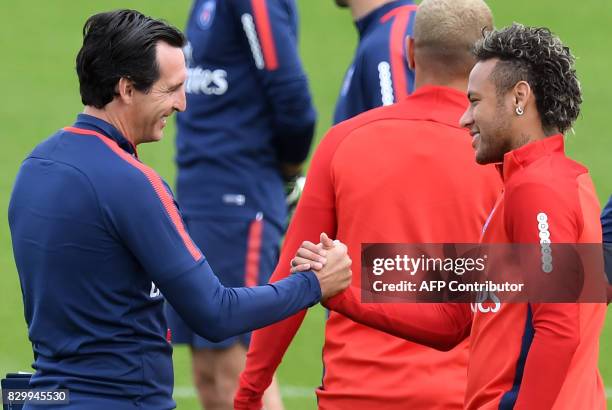 Paris Saint-Germain's Brazilian forward Neymar shakes hands with Paris Saint-Germain's Spanish head coach Unai Emery during a training session at the...