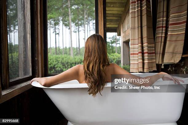 young woman sitting in bathtub - baignoire sur pieds photos et images de collection