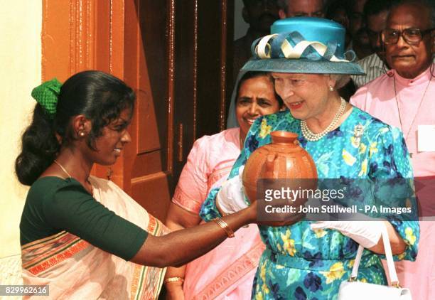 The Queen accepts a clay water pot from Gayathiri Oliviet aged 19, outside the St Francis Church in Kochi, south west India.