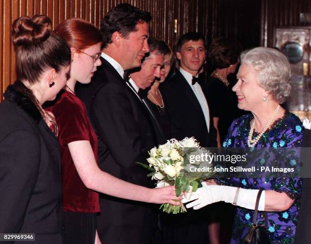 Britain's Queen Elizabeth II, is presented with a posy by 15-year-old Sarah Mowat, a patient of Great Ormond Street Hospital upon her arrival at the...