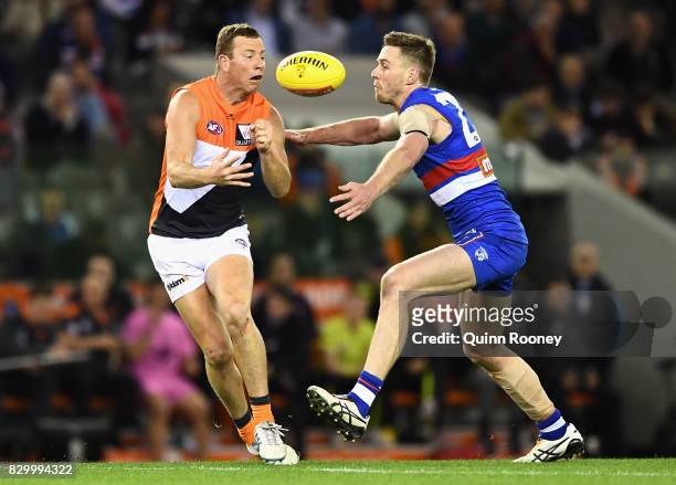 Steve Johnson of the Giants handballs whilst being tackled by Jordan Roughead of the Bulldogs during the round 21 AFL match between the Western...