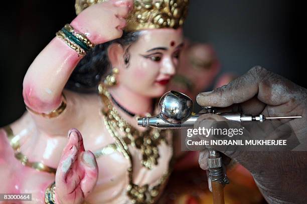 An artisan uses an airbrush to apply a coat of glitter on an idol of the Hindu goddess Durga ahead of the upcoming festival of Navratri in Mumbai on...