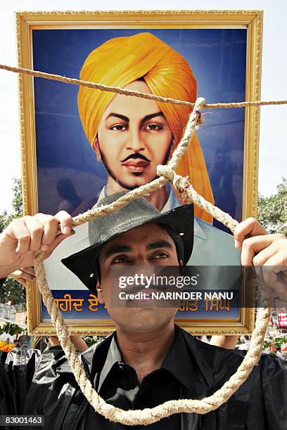 Indian Sikh youth Daljit Singh, dressed as Indian freedom fighter Bhagat Singh, holds a noose in front of a portrait of the freedom fighter during a...