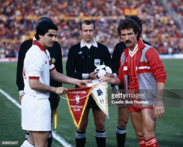 Liverpool captain Graeme Souness and Roma's Agostino Di Bartolomei exchange pennants, watched by referee Erik Fredriksson, before the European Cup...