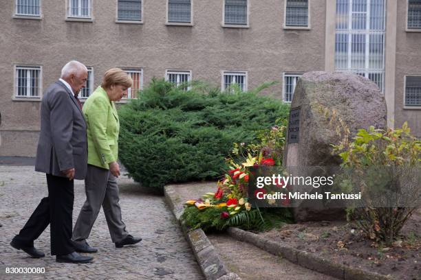 German Chancellor Angela Merkel and with former Prisoner Arno Defke lay a wreath while she visits the former prison of the East German, communist-era...