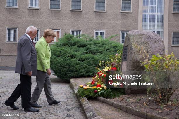 German Chancellor Angela Merkel and with former Prisoner Arno Defke lay a wreath while she visits the former prison of the East German, communist-era...
