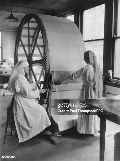 Women operate the new stretching machine for surgical dressing at the Red Cross headquarters in Cincinnati, Ohio, circa 1915. The machine, which was...