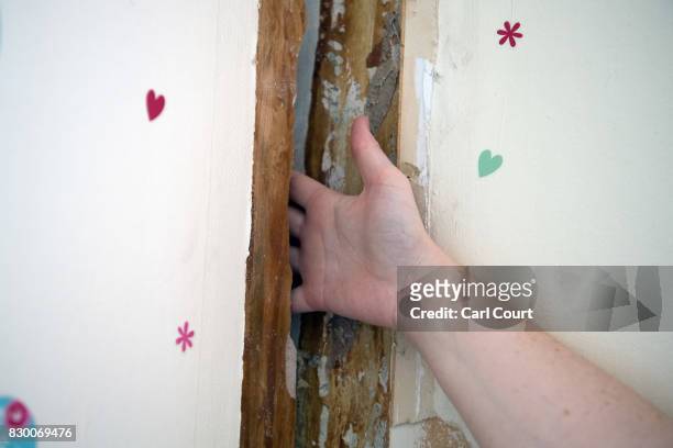 Resident pushes her hand through a gap between walls in her flat on the Ledbury Estate on August 11, 2017 in London, England. Hundreds of residents...