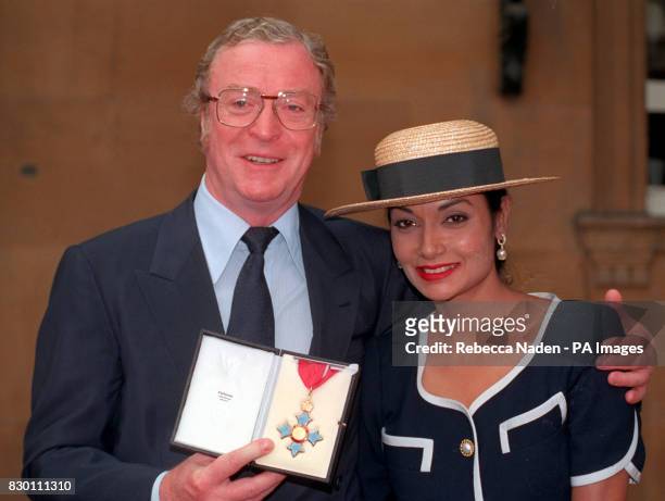 PA NEWS PHOTO 22/7/92 MICHAEL CAINE AND WIFE SHAKIRA HOLDING HIS CBE AT BUCKINGAM PALACE, LONDON