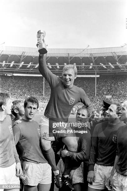 England's triumphant 1966 World Cup final captain Bobby Moore chaired by hat-trick hero Geoff Hurst and Ray Wilson as he salutes the crowd with the...