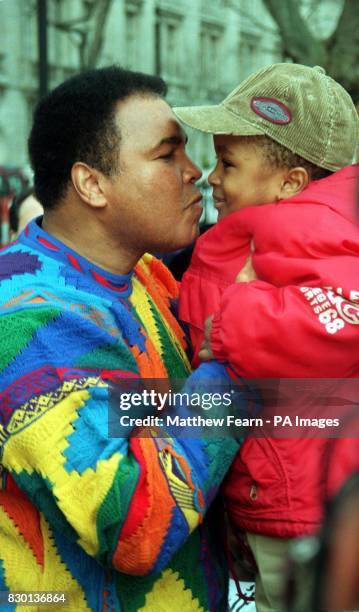 Boxing legend Muhammad Ali gives a child a kiss before he lays a wreath at a monument in London as part of a campaign by the Jubilee 2000 Coaltion to...