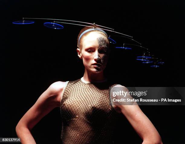 Model presents a sleeveless net shirt and 'mobile' hat with blue perspex discs from designer Philip Treacy, during his London Fashion Week show.