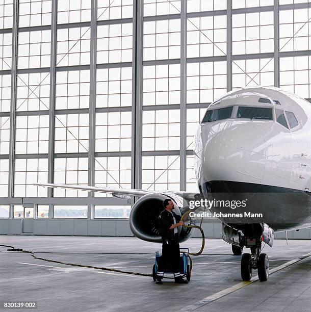 man refuelling commercial aircraft in hangar - aircraft refuelling stock pictures, royalty-free photos & images