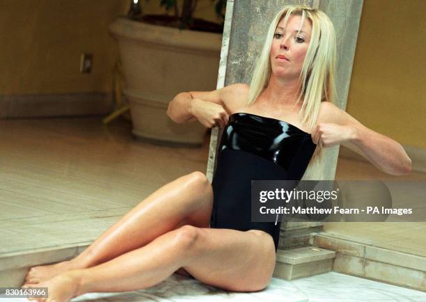 Society girl Tamara Beckwith pulls herself back into the black patent swimsuit, as she models one of the costume's from new range of swimwear by Liza...