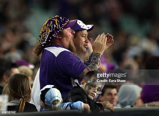 Storm fan celebrates as a young Sharks fan can't watch after the Storm scored another try during the first NRL Preliminary Final match between the...
