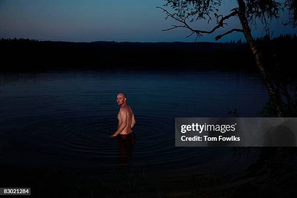 man in lake at night - hüfttief im wasser stock-fotos und bilder