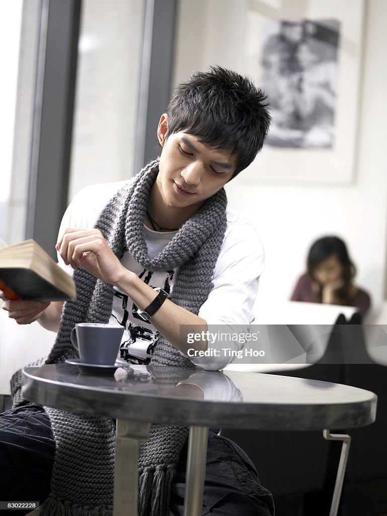 Man with book in cafe, looking at watch