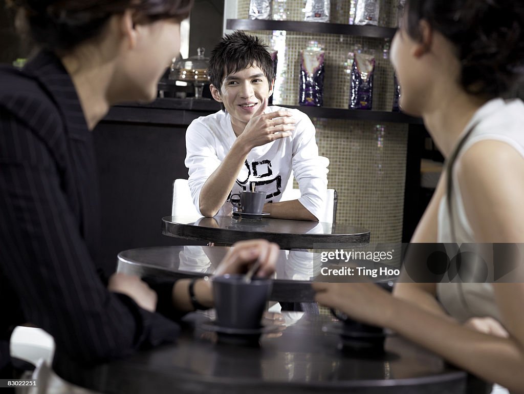 Man talking to two women in cafe, focus on man